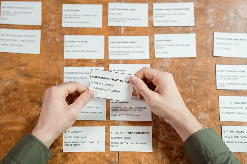 Hands arranging index cards in rows on a wooden table