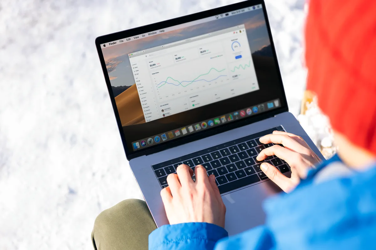 Person reviewing a web analytics dashboard with revenue and traffic charts on a laptop