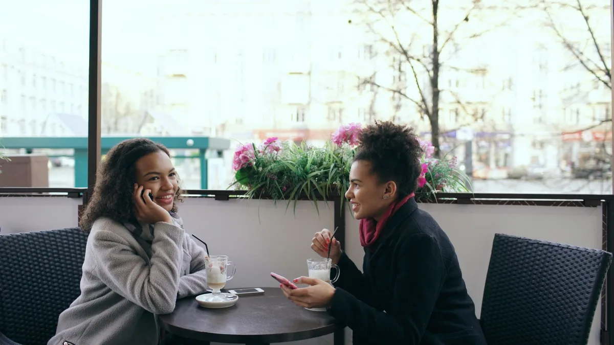Two friends chatting over coffee at an outdoor cafe table