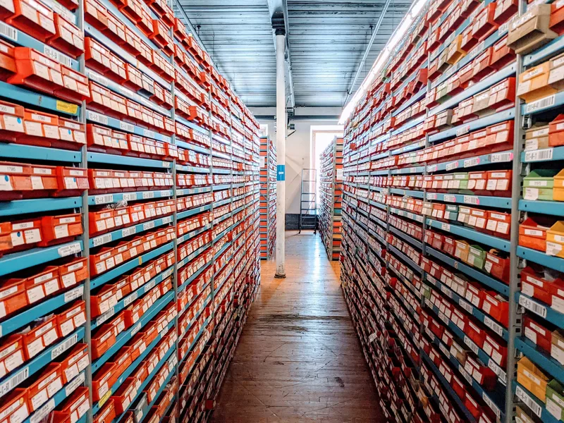 warehouse aisle with organized product shelving, each slot holding a different SKU