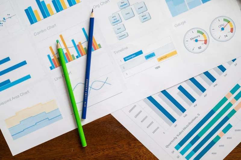 Flat lay of business charts and colored pencils on a wooden table representing customer data analysis